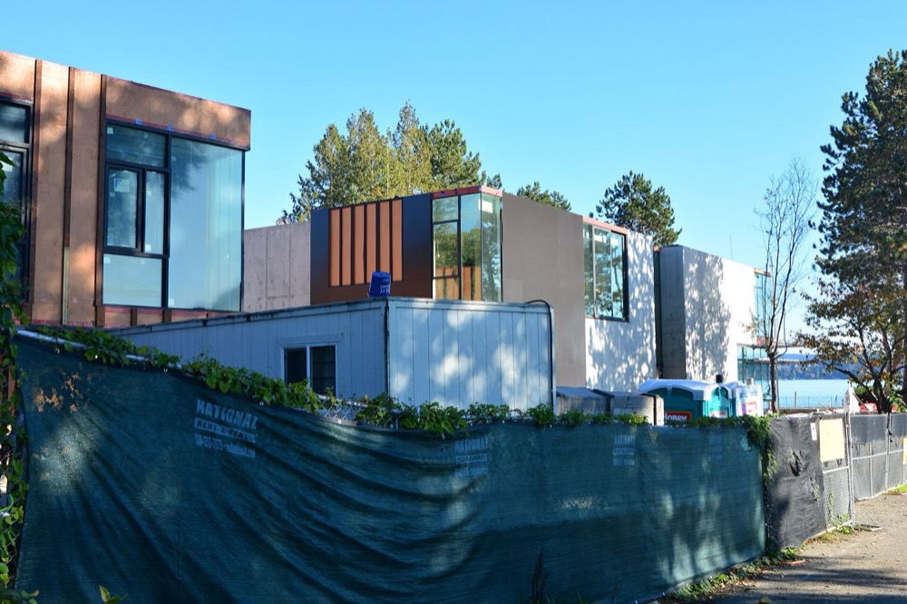 New houses under construction on the Lake Washington shore in Seattle, their wood framing and roof trusses exposed.