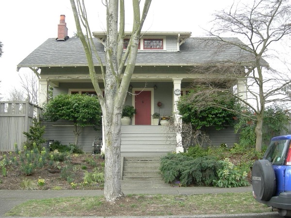 A typical single-family house in Seattle's Bryant neighborhood, with a front yard and sidewalk — the kind of lot a pre-approved DADU plan has to fit behind.